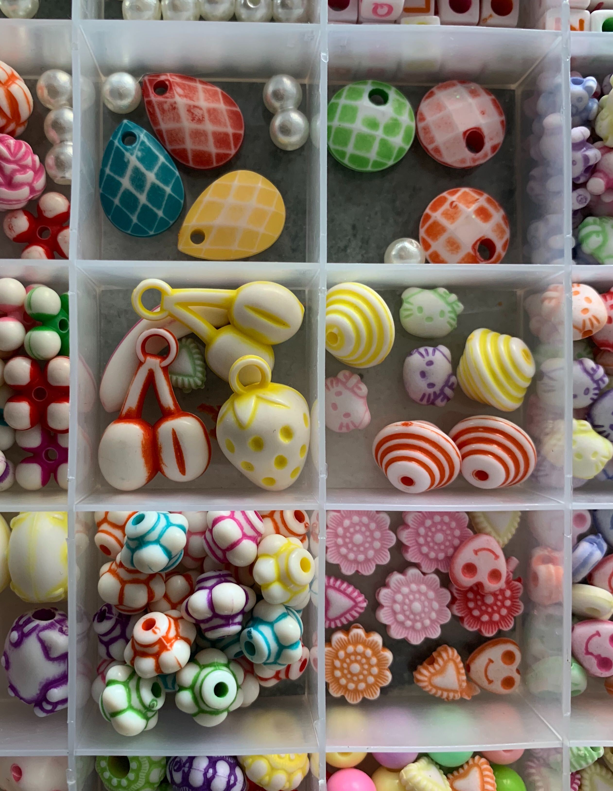 A plastic case divided into squares each holding a variety of colored beads.