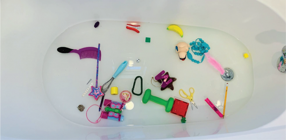 A variety of objects in a bathtub filled with water.