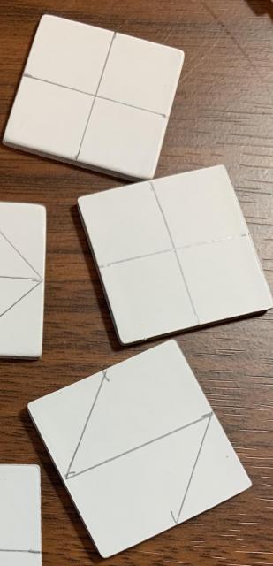 Uncolored tiles with patterns drawn on them ready to be painted.