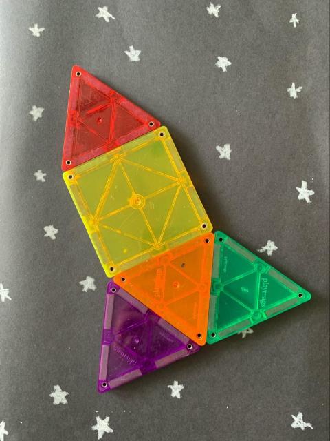 A spaceship made of shapes. 1 triangle for the top. 1 square for the body. The bottom is 3 triangles.