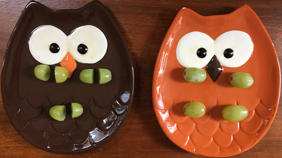 Nina's grapes are on a brown plate that looks like an owl. Each grape is cut into 2 equal pieces. There are 6 pieces in all. Dan's grapes are on an orange plate that looks like an owl. The grapes are in 2 rows. Each row has 2 grapes.