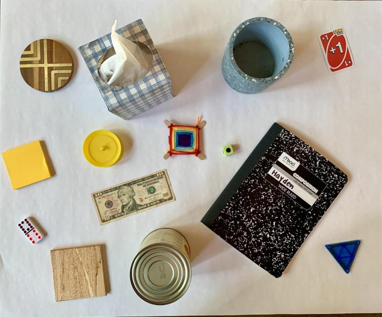 We found these shapes. A round wooden coaster. A square box of tissues. A mug. A playing card. A pad of square sticky notes. A round lid. A square yarn craft. A die. A domino. A $10 bill. A notebook. A square wooden coaster. A food can. A triangle shape block.
